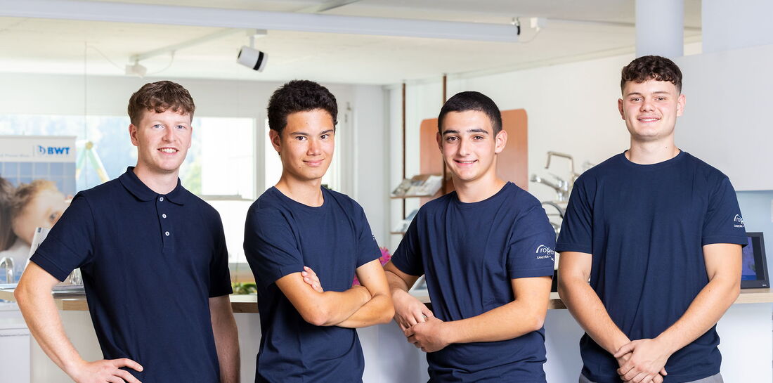 4 junge Männer mit blauem T-Shirt vor einer Theke